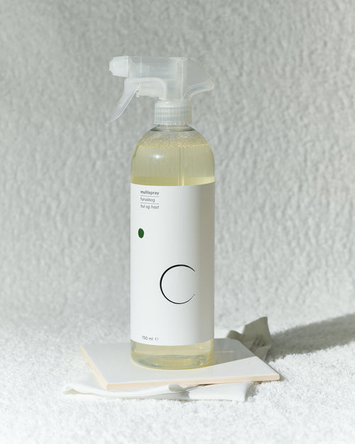Spruteflaske med multispray i duften furuskog foran hvitt håndkle.